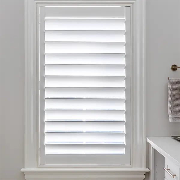 A Modern 4.5" Louver shutter with hidden tilt feature covers a window in a bathroom.