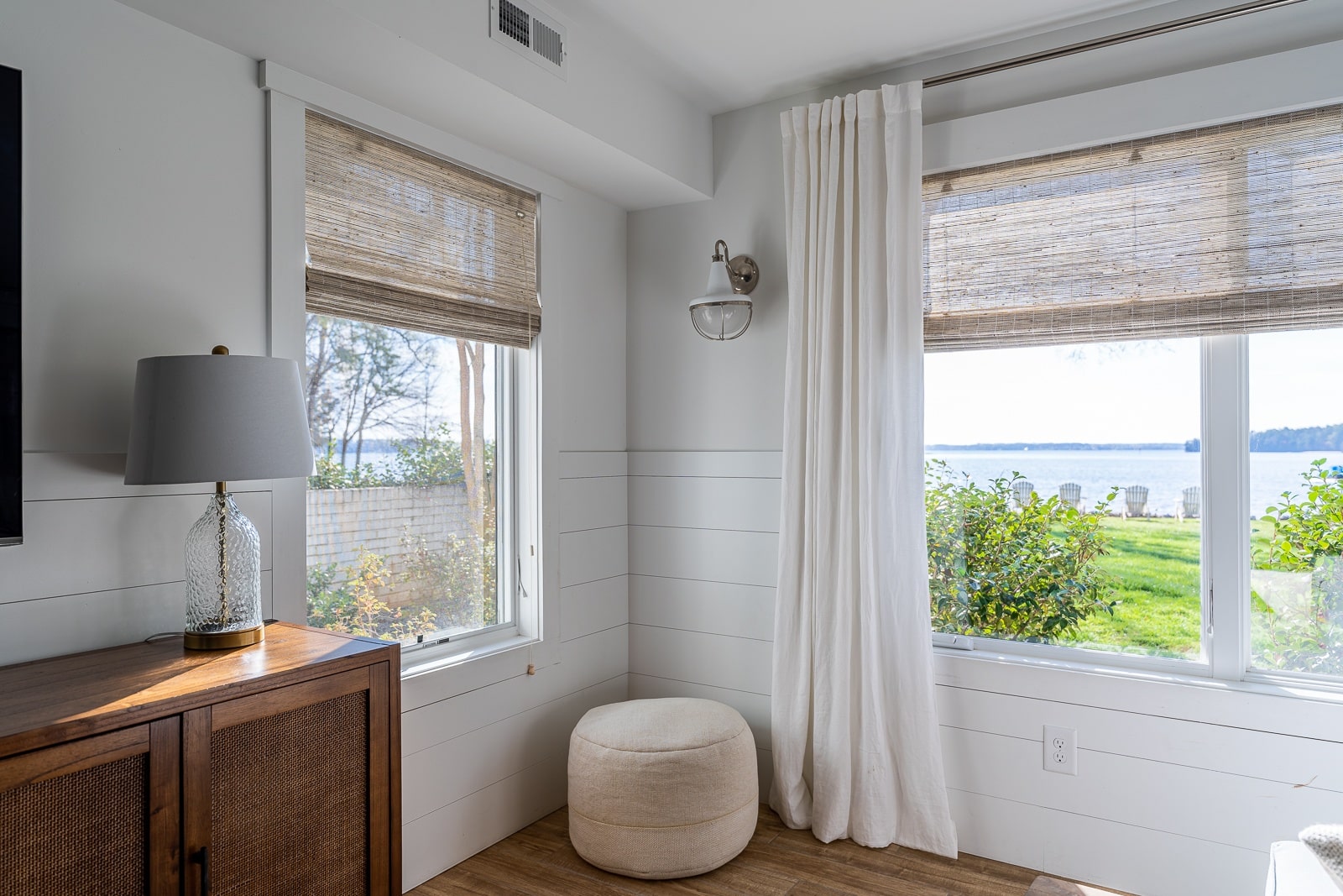 Grey light filtering woven wood shades in an open modern living room overlooking lakefront property