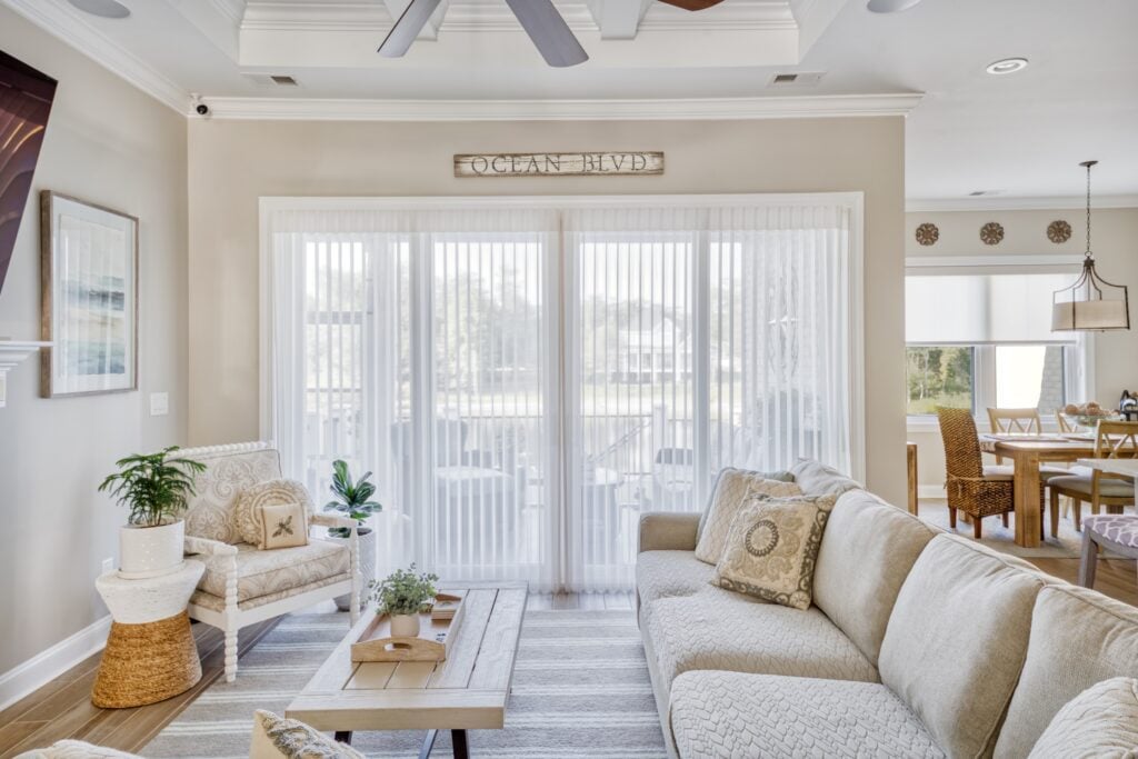 Cozy living room with neutral tones, a large Luminette shade over a sliding glass door, and view to dining area.