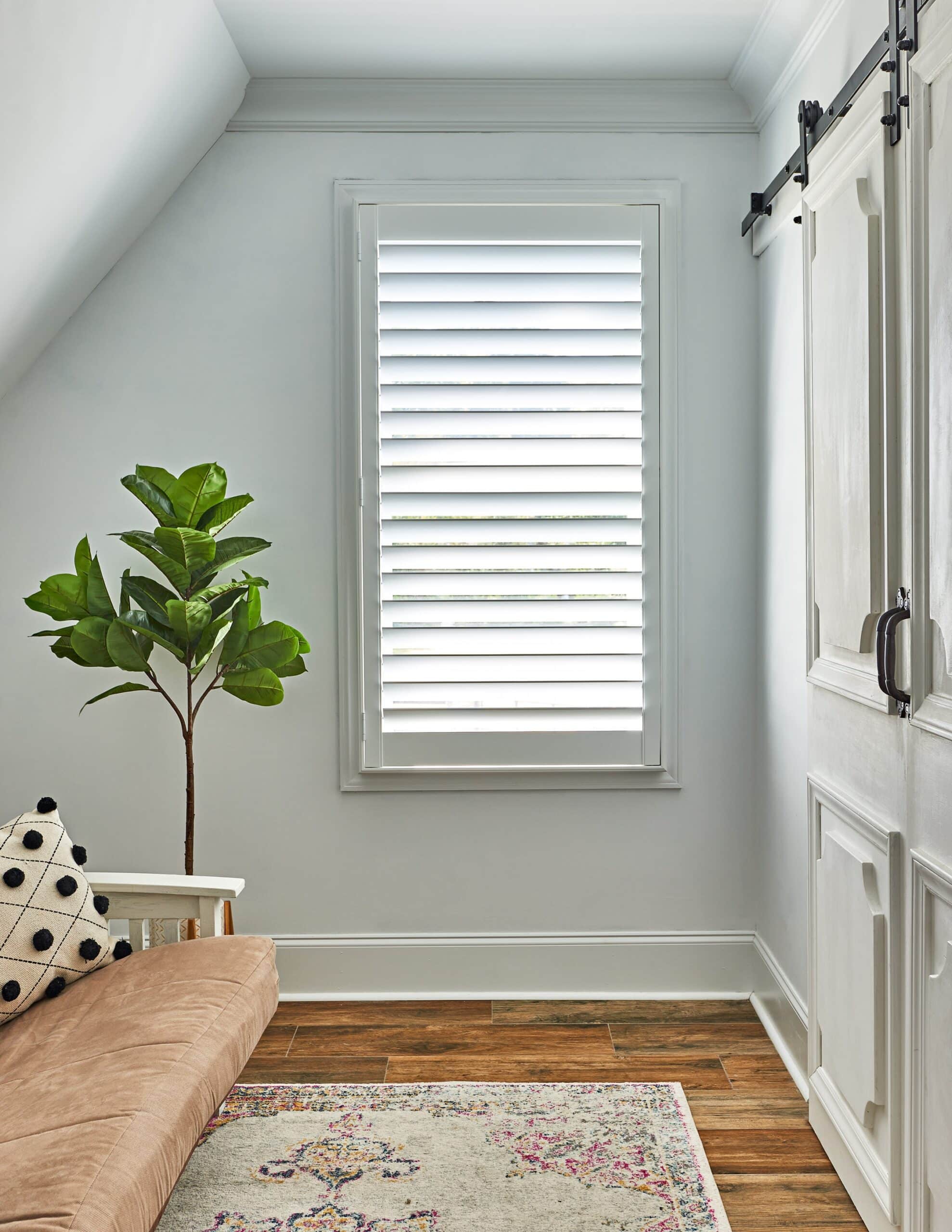 Single wood shutter next to a sliding barn door in a bedroom