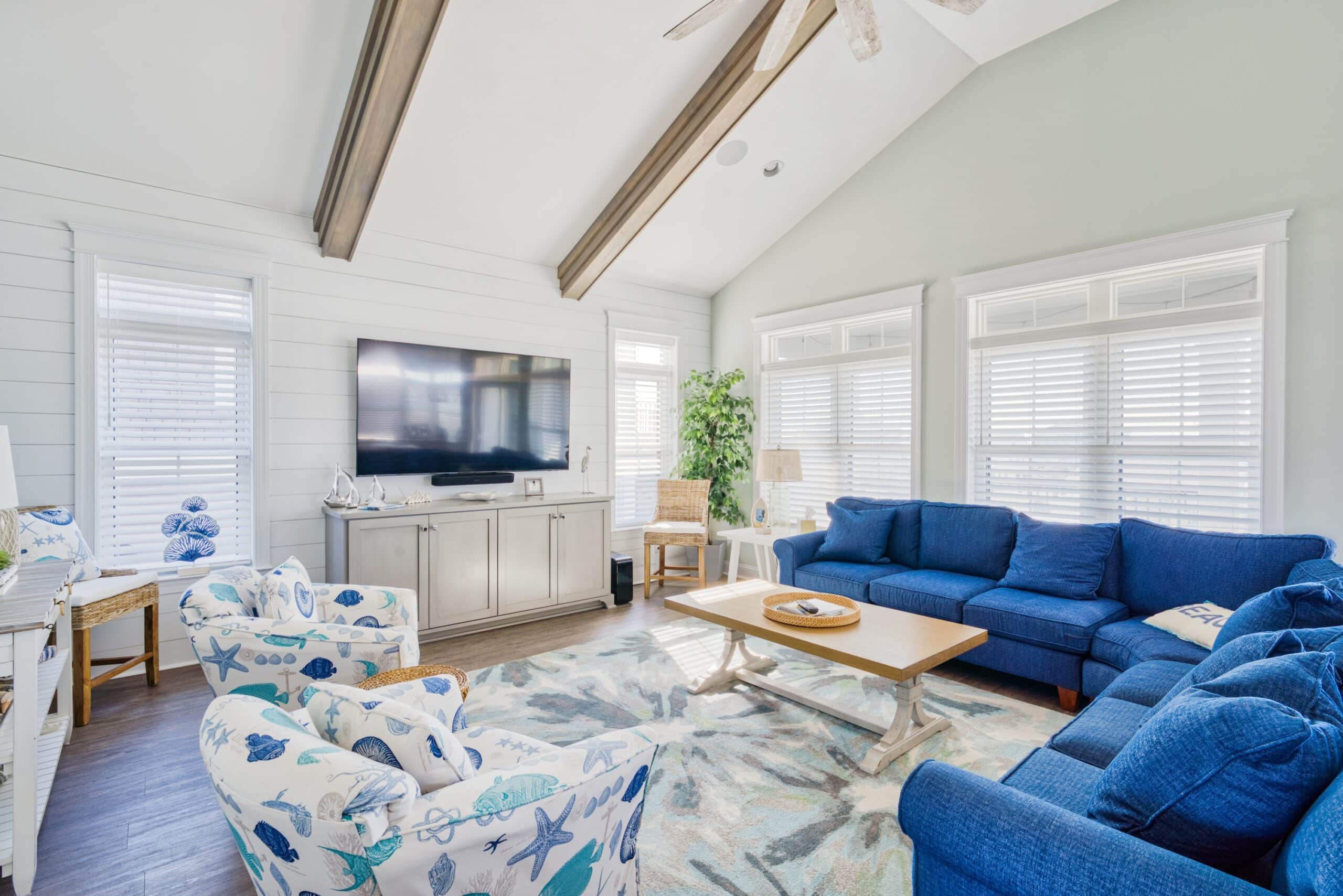 Large living room at a beach house with white blinds and blue couch