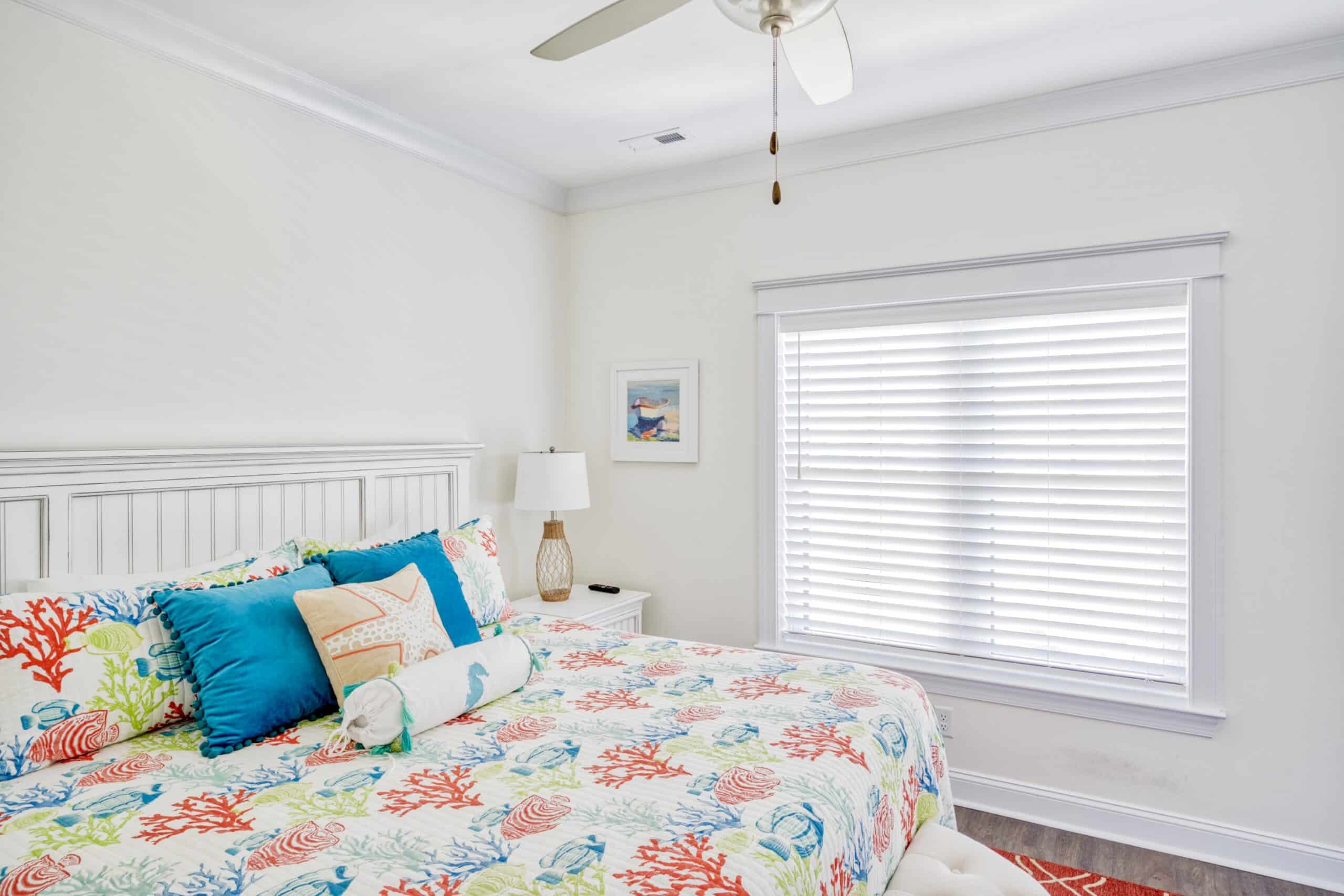 Large single blind on window in guest bedroom with coastal themed bed spread