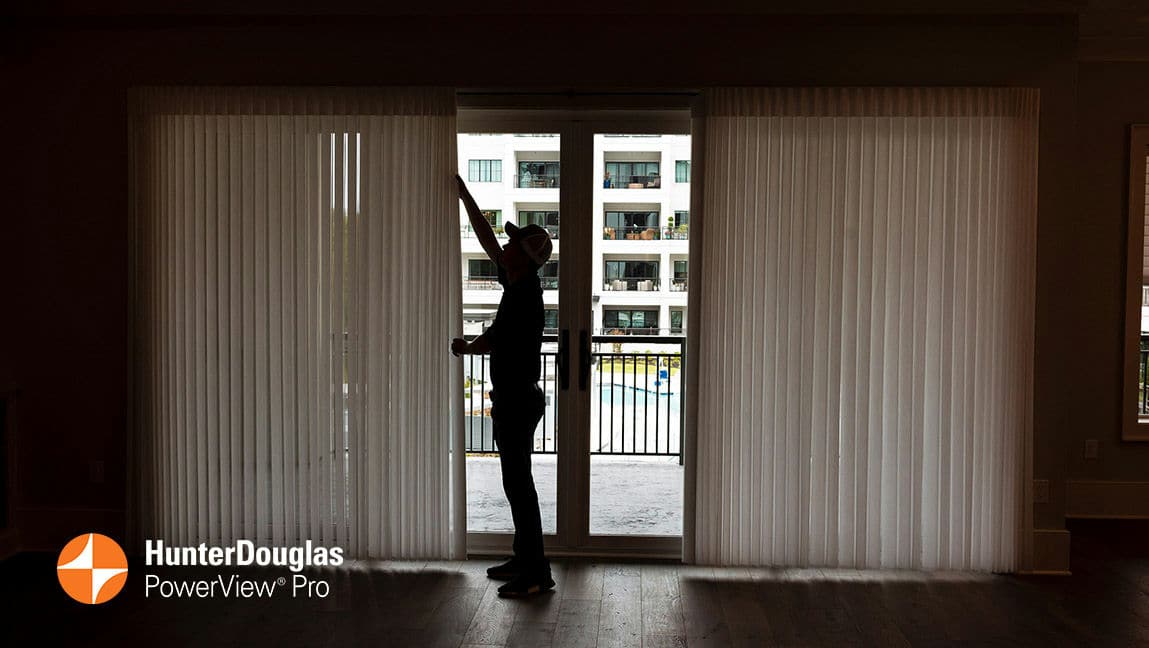 A young installer places the final touches on a blind over a fabric sliding door