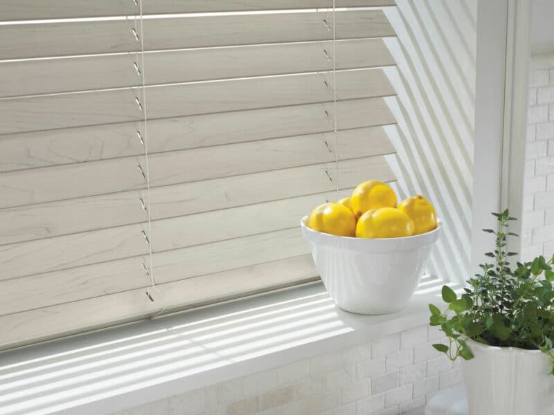 Wood grain alternative blinds hanging in a kitchen window