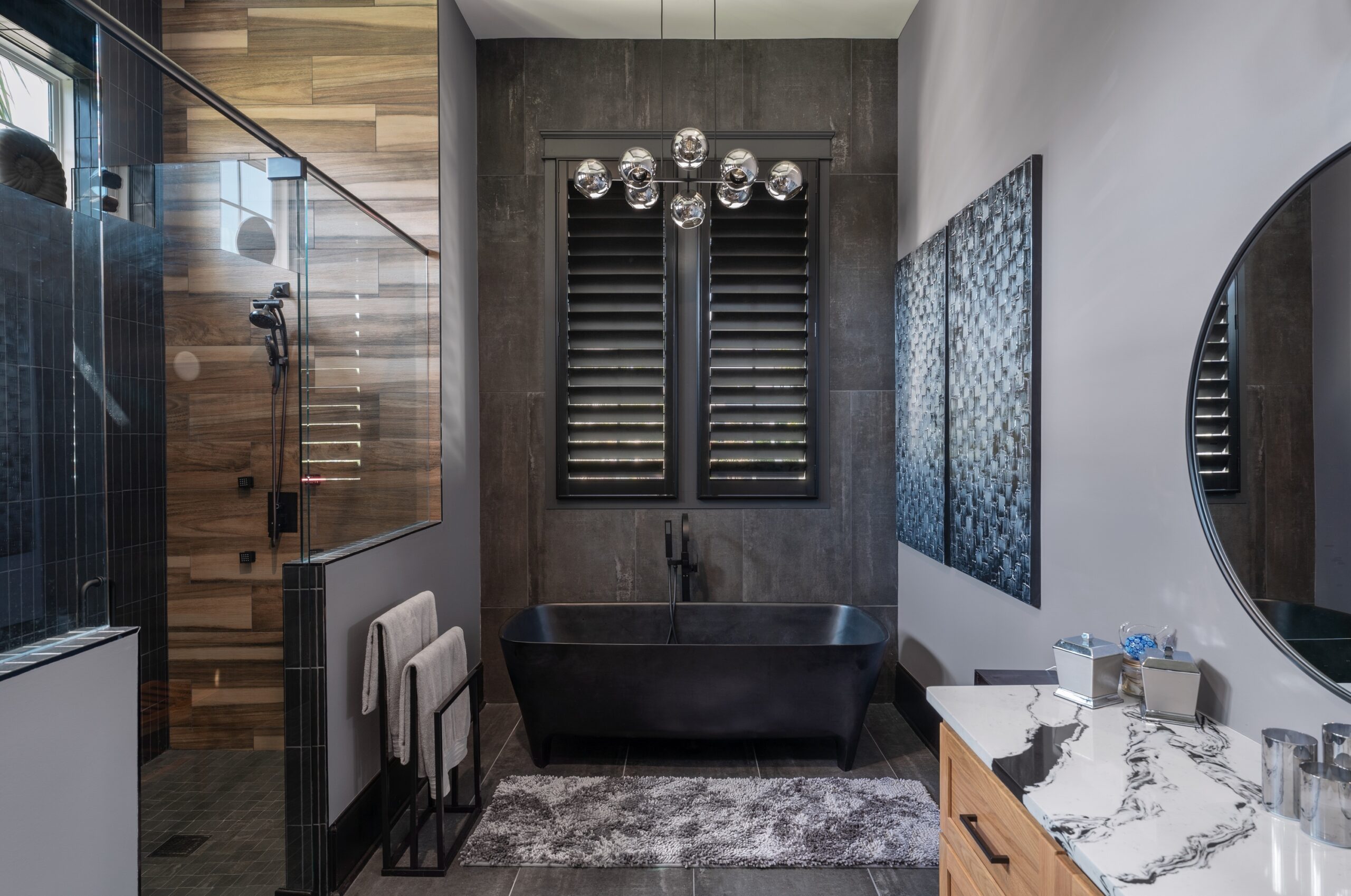 Black hidden tilt plantation shutters over a free standing tub in a modern dark colored bathroom