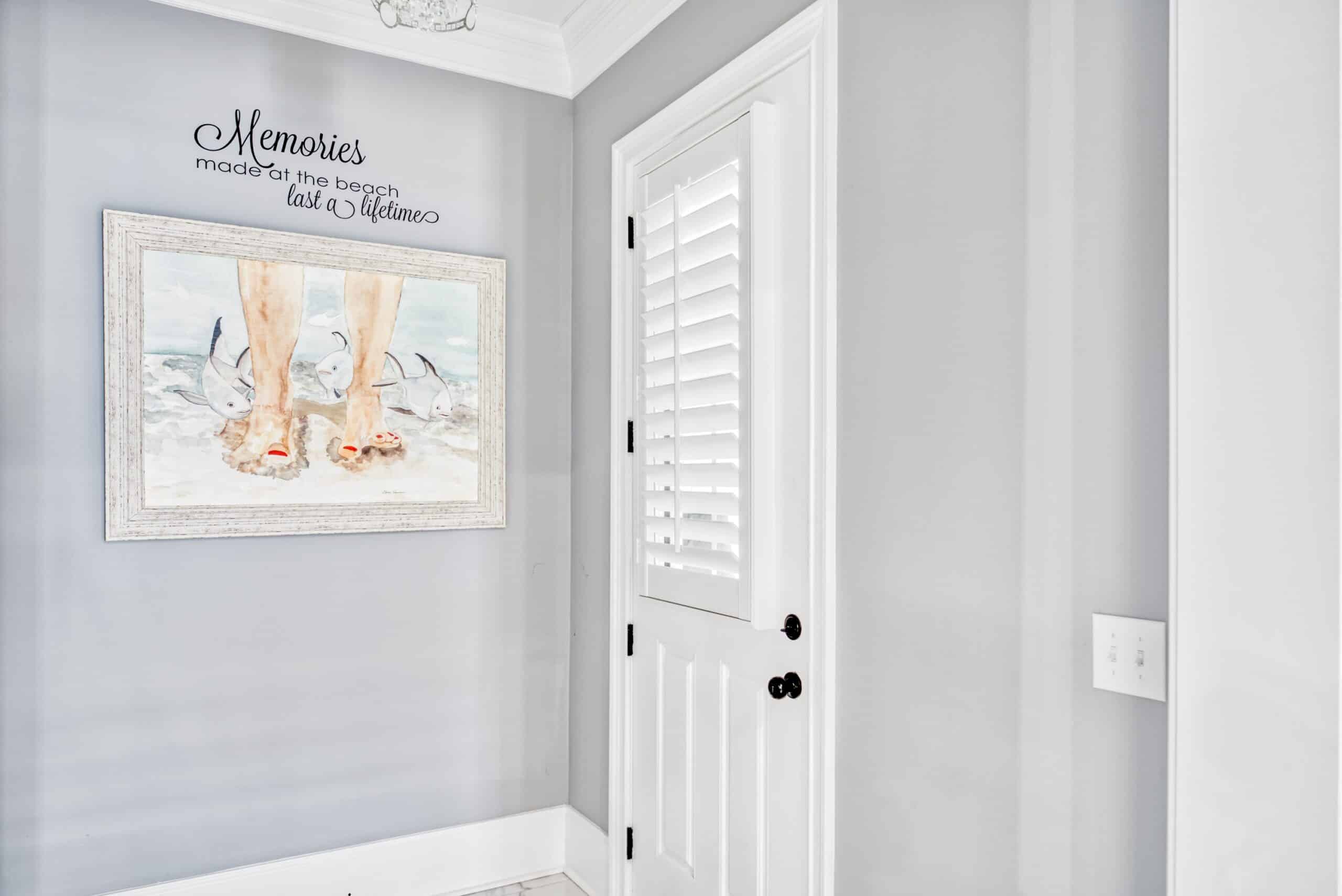 An open contemporary entry way with a plantation shutter on the door and wall art