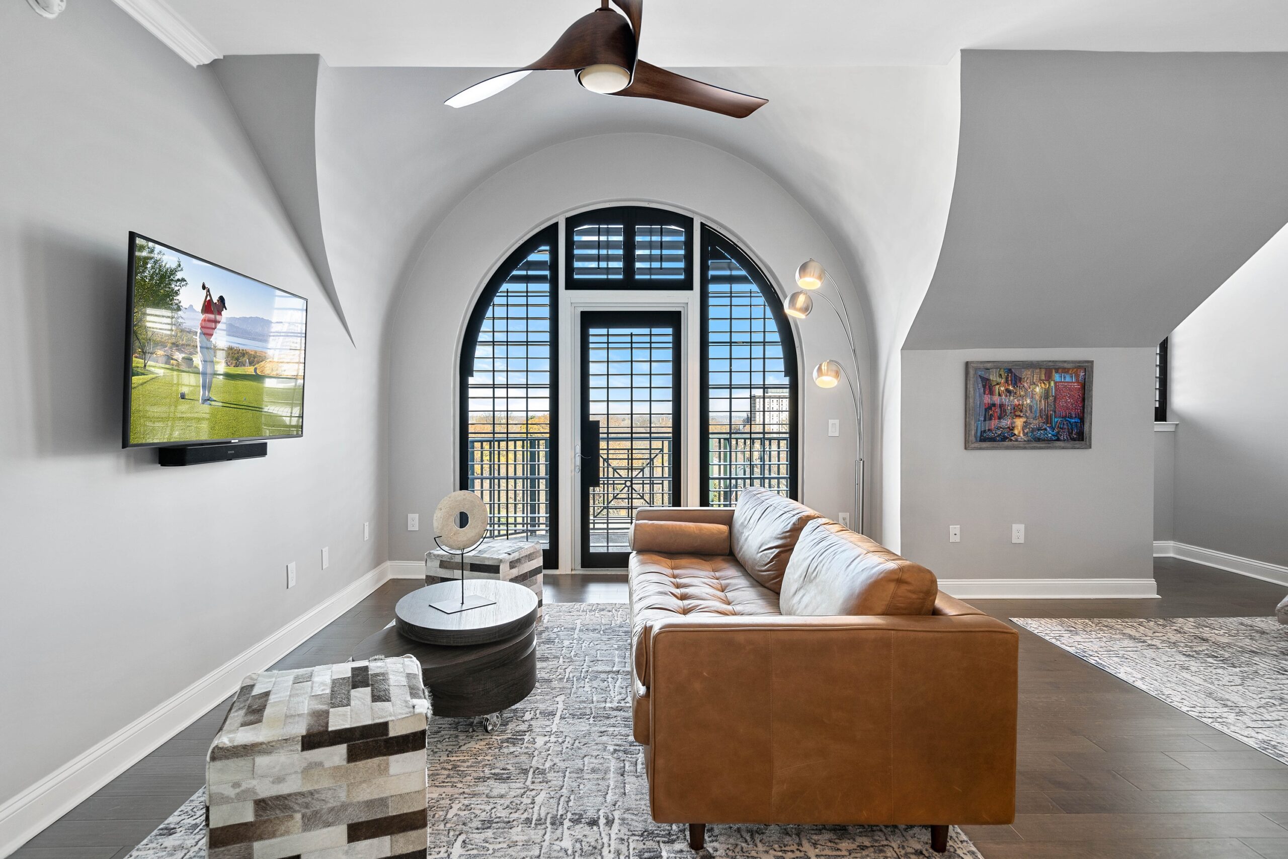 Large arched window and door in a modern condo, framed by black custom wooden shutters.