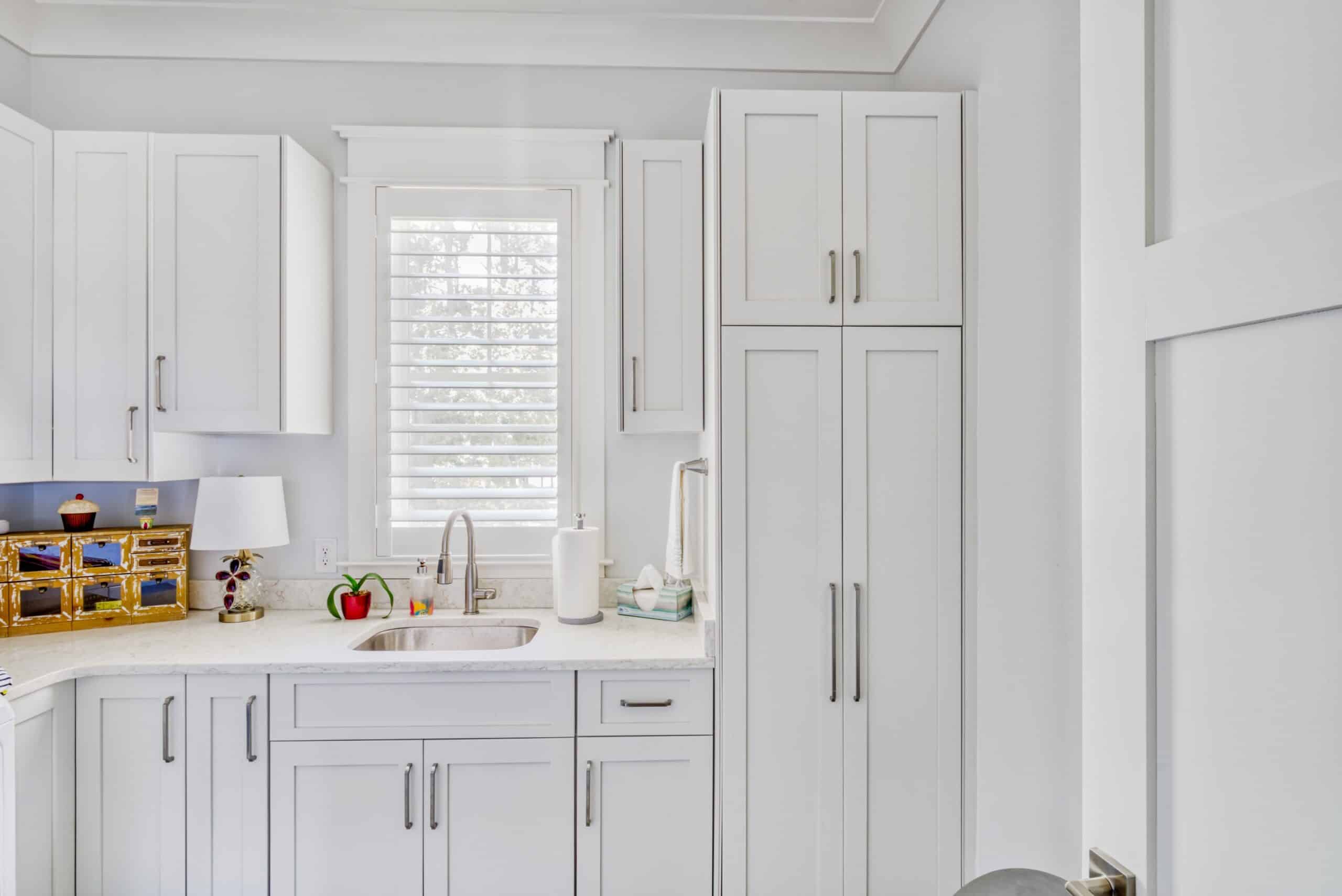 A traditional kitchen with white cabinets and a hidden tilt plantation shutter above the sink