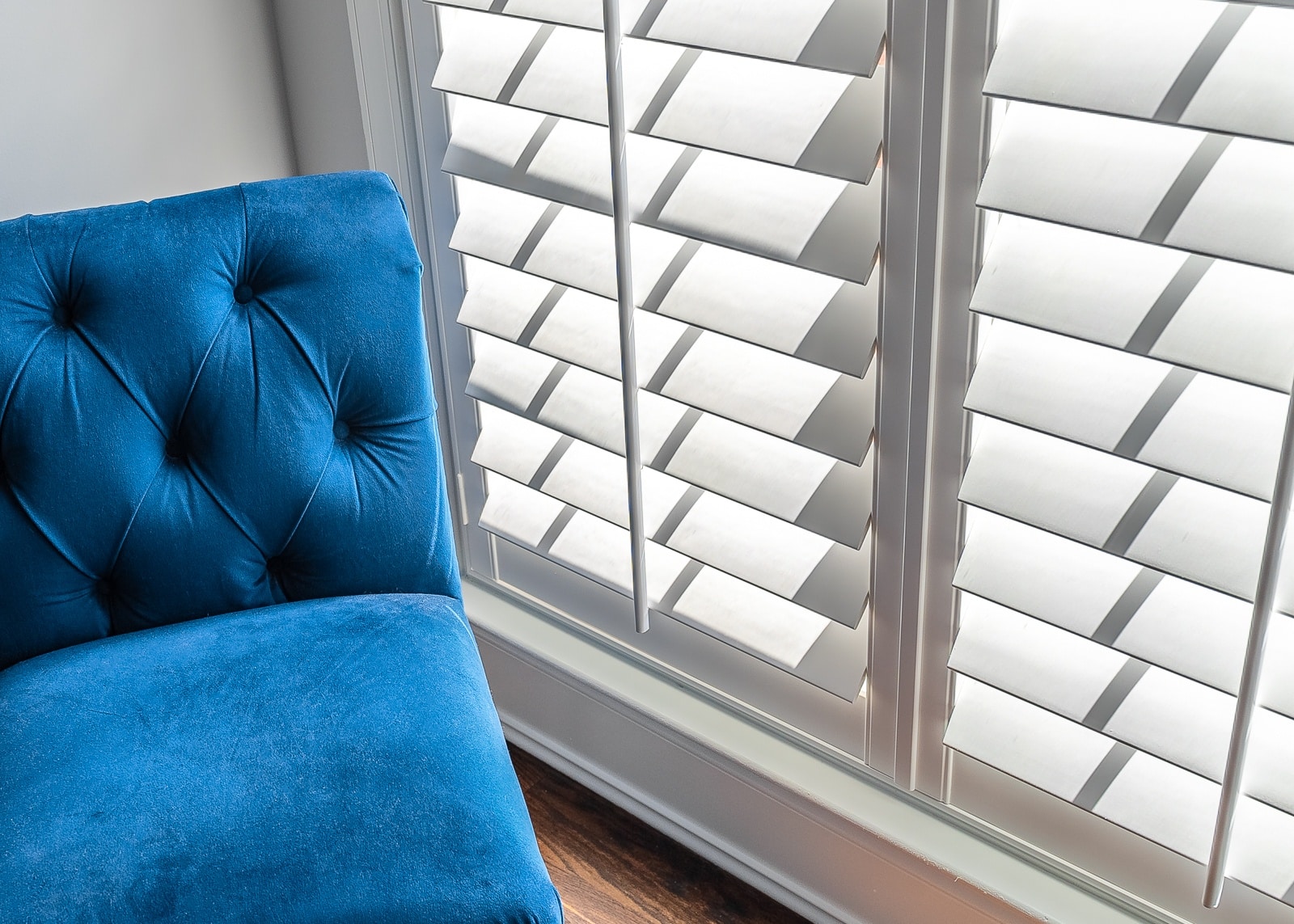 White plantation shutters next to a blue chair