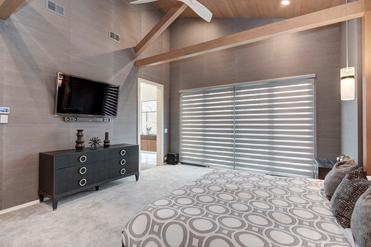 Modern bedroom with gray textured walls, banded shades, wooden beams, and contemporary furnishings.