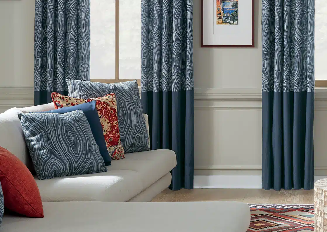 Blue marbled pillows on a sofa next to matching drapes.