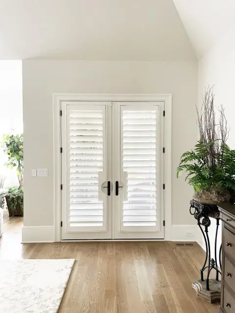 Hidden Tilt Plantation Shutters cover a set of french doors, with a custom cutout around the levered door handles.