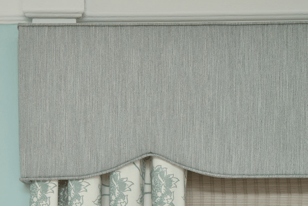 Light blue cornice atop floral drapery and a woven roman shade