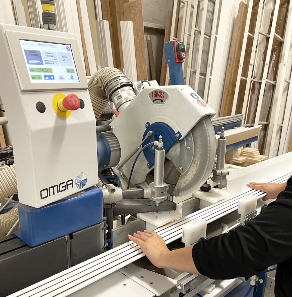 A technician cutting plantation shutter lovers with an automated radial arm saw.