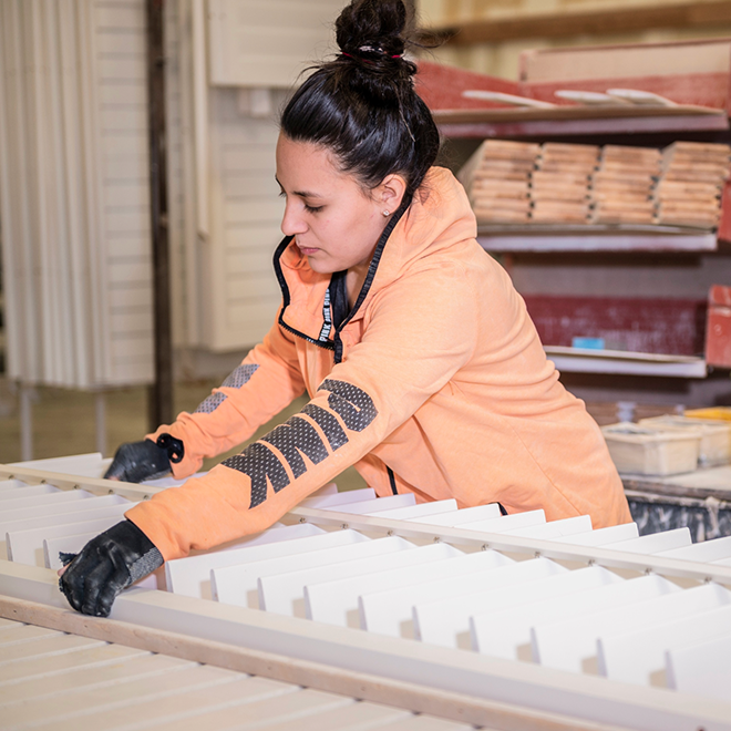 A worker assembles all the cut shutter pieces into a finished panels