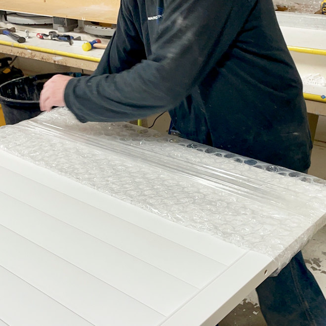 A worker wraps a plantation shutter in bubble wrap