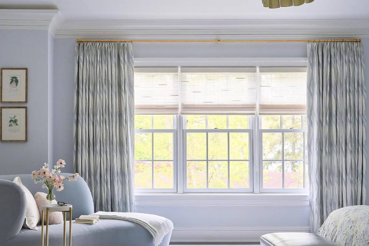 Living room with light blue color scheme and Hunter Douglas Alustra® Woven Textures® adorning large windows