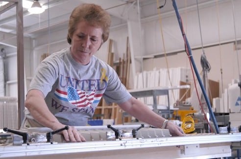 A woman working in a factory to build custom shutters