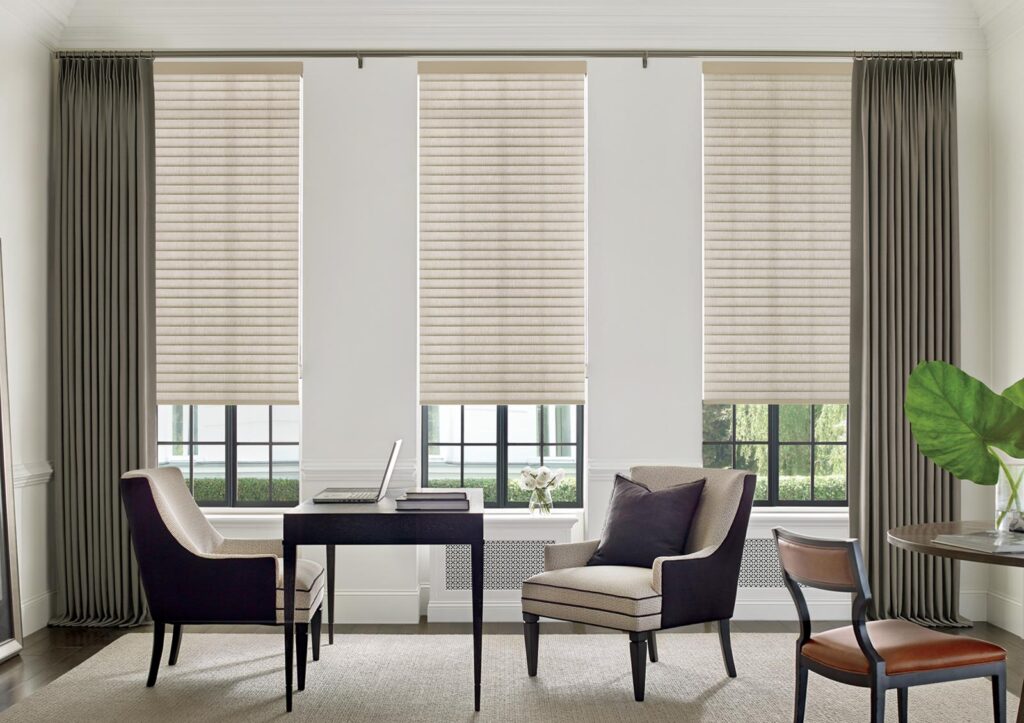 home office with neutral colored cellular roller shades for energy efficiency and olive green drapery panels