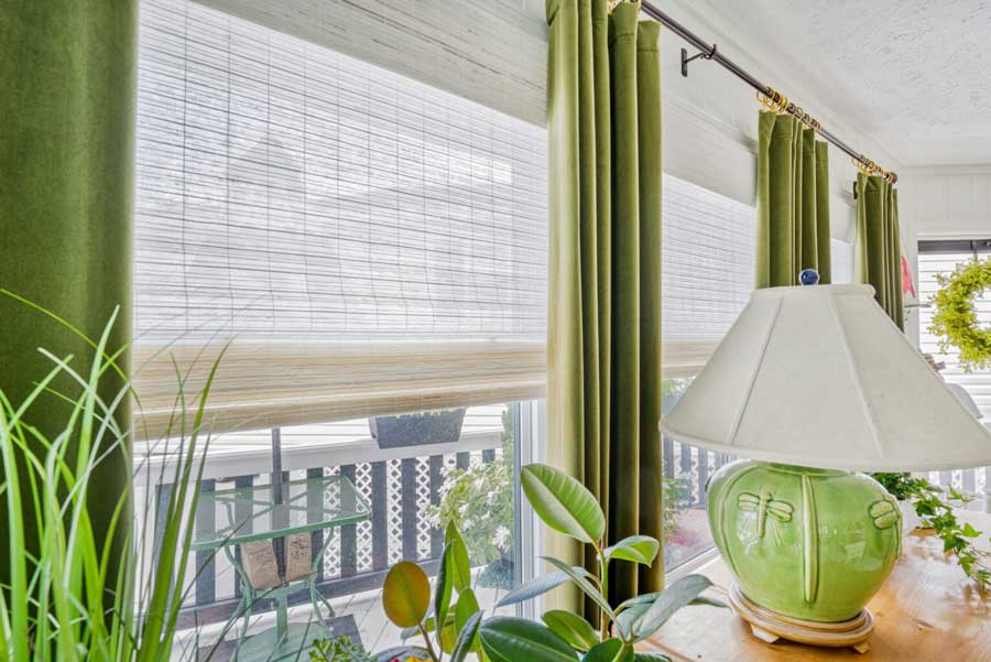 woven wood shades with lime green drapery panels on large living room windows