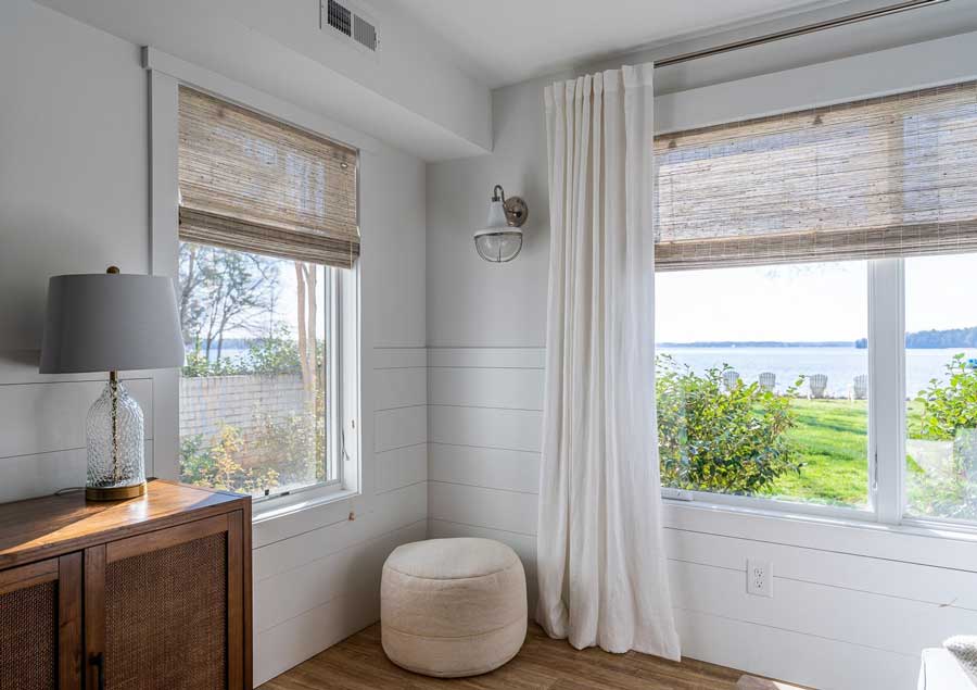 light filtering woven wood shades with white drapery panels in a living room overlooking lakefront property in Carolinas